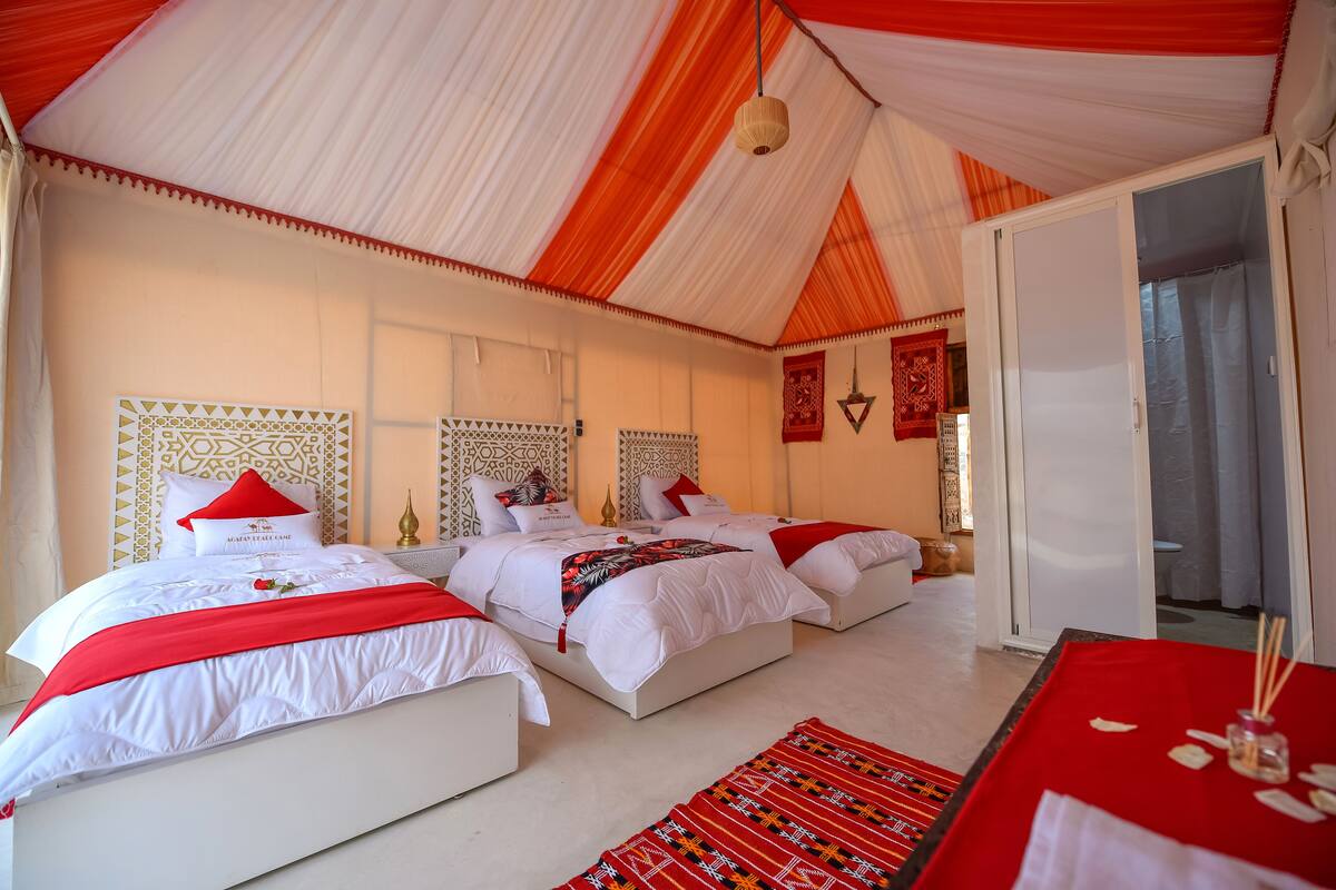 A room with two beds, white bedding, red accents, and patterned headboards.