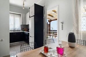 Une cuisine moderne avec des meubles de couleur noire, une table à manger en bois et une vue sur l’extérieur.