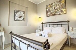 A neatly made bed with white linens and rolled towels, a dark wooden headboard, and a wall-mounted light fixture.