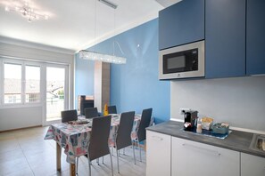 A modern kitchen with a dining area, a microwave, and a dining table set for four. - Apartment 'Glamuor 1' with Private Terrace, Wi-Fi and Air Conditioning (Sanremo)