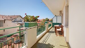 Un balcone con tavolo e sedie, piante in vaso e vista sugli edifici circostanti.
