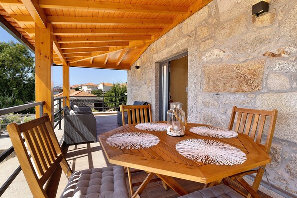 A wooden table with four chairs, a glass pitcher, and a stone wall. - Holiday Home 'Da Lage' with Sea View, Wi-Fi and Air Conditioning (Castelo do Neiva)