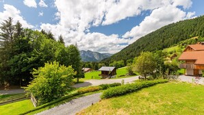 A rural landscape with a road, a wooden house, and a mountain in the background. - Chalet "L'Oréade" with Mountain Views, Private Terrace and Wi-Fi (Manigod)