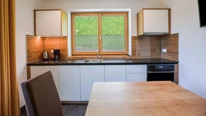 Eine moderne Küche mit großem Fenster, Holzschränken und einem Esstisch.