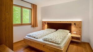 Ein Schlafzimmer mit einem hölzernen Bett, einem Nachttisch, einem Fenster mit Vorhängen und einer Deckenleuchte.