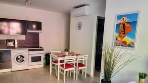 A modern kitchen with a washing machine, a dining table with chairs, and a potted plant.