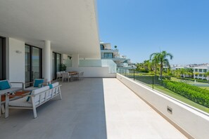 A balcony with outdoor furniture, a clear view of the surrounding buildings, and a well-maintained garden.