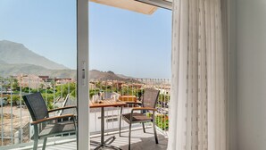 A balcony with a table and chairs, a view of a cityscape, and a mountain in the distance. - Vacation Home 'Suite Mirador Del Galeón' with Sea View, Wi-Fi and Air Conditioning (Adeje)