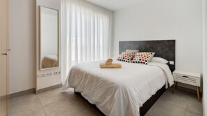 A bedroom with a bed, a bedside table, a mirror, and a window with curtains. - Vacation Home 'Suite Mirador Del Galeón' with Sea View, Wi-Fi and Air Conditioning (Adeje)