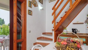 Una escalera con barandillas de madera, un área de comedor con una mesa y sillas, y una cesta decorativa sobre la mesa.