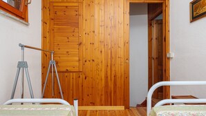 Una habitación con dos camas, una puerta de madera, un trípode y una mesita.