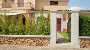 Un edificio de dos plantas con un muro de piedra, un balcón y una puerta.