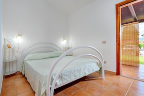 A bed with a white metal frame, a green bedspread, and two wall-mounted lamps. - Villa 'Grazia 1' with Private Terrace and Private Garden (San Teodoro)