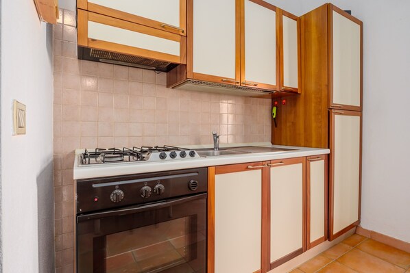 Una cocina con estufa a gas, horno y encimera blanca.