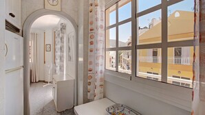 A hotel room with a view of the city, a window with a curtain, a small table, and a fan.