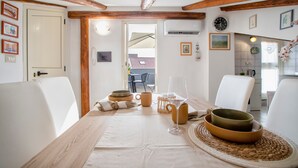 A dining area with a table set for two, featuring a wooden table, white chairs, and a view of the outside. - Apartment 'Isola Di Giava Holiday' with Private Terrace, Wi-Fi & Air Conditioning (Sorso)