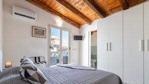 A bedroom with a bed, a TV, an air conditioner, and a view of the outside. - Apartment 'Isola Di Giava Holiday' with Private Terrace, Wi-Fi & Air Conditioning (Sorso)