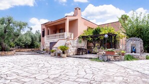 A building with a stone-paved courtyard, a covered seating area, and a statue. - Villa 'Venza with Pool' with Private Pool, Private Garden and Wi-Fi (Ostuni)