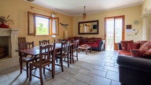 A dining area with a wooden table and chairs, a sofa, and a fireplace. - Villa 'Venza with Pool' with Private Pool, Private Garden and Wi-Fi (Ostuni)