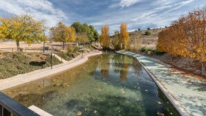 A clear water feature with a wooden walkway and benches, surrounded by trees with autumn foliage. - Holiday Home "Casa Rural Atalaya-Coy" with Mountain Views, Private Terrace and Garden (Coy)