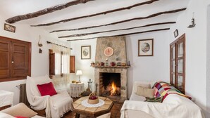 A cozy room with a fireplace, wooden beams, and a stone wall. - Holiday Home "Casa Rural Atalaya-Coy" with Mountain Views, Private Terrace and Garden (Coy)