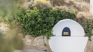 A white wall with a small, dark archway and a stone wall covered in green foliage. - Holiday Home "Casa Rural Atalaya-Coy" with Mountain Views, Private Terrace and Garden (Coy)