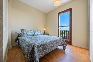 A bedroom with a bed, a nightstand, a lamp, and a window with a view. - Vacation home "Casa Manolo" with communal pool, private terraces & communal garden (torredembarra)