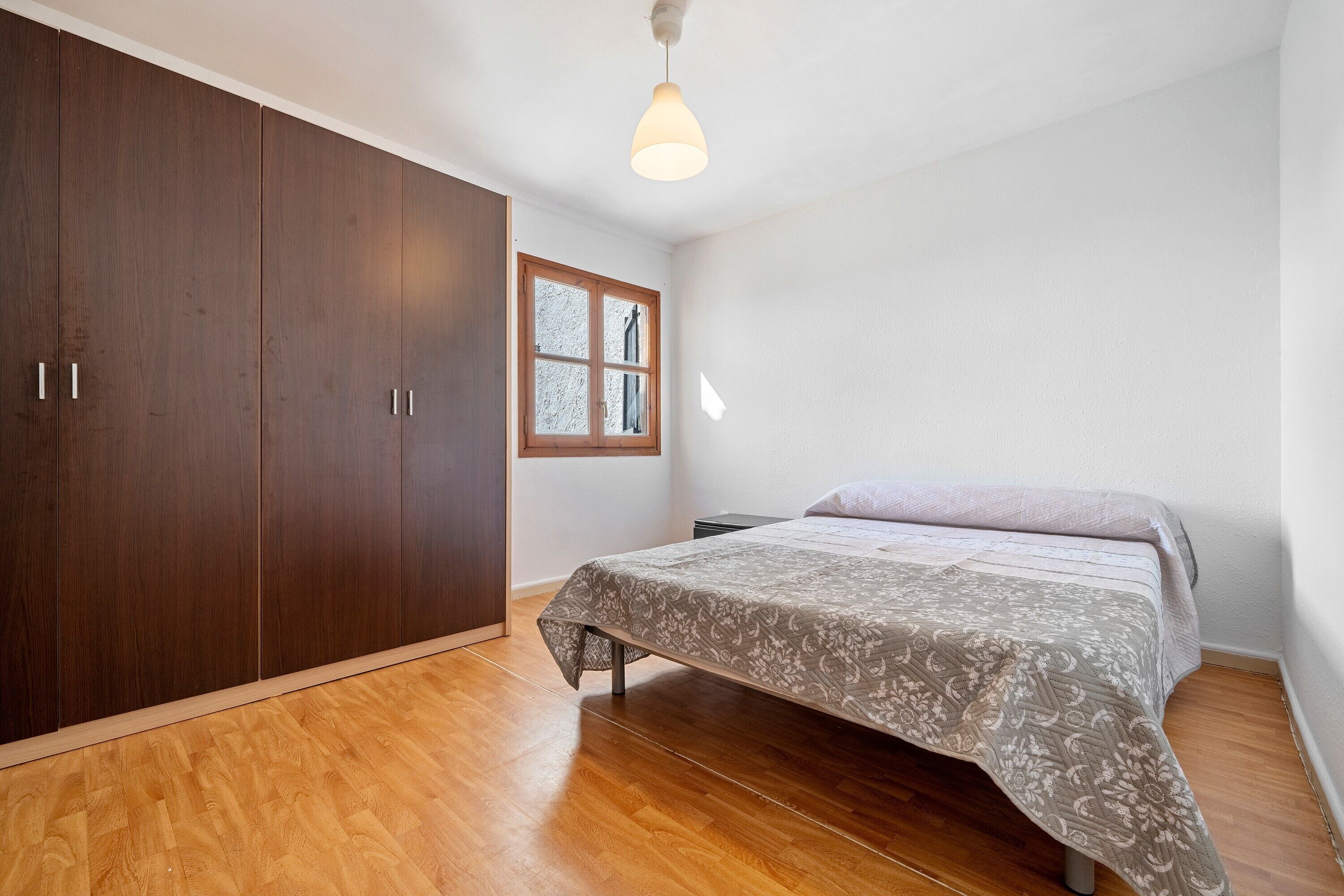 Une chambre à coucher avec un lit, une armoire en bois et une fenêtre.