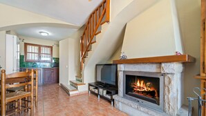 Una sala de estar con chimenea, televisor y comedor con sillas.