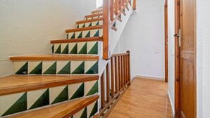 Una escalera de madera con barandilla que lleva a una puerta.