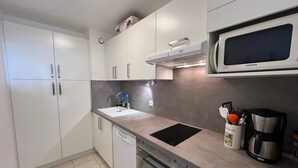 Une cuisine moderne avec des meubles blancs, un four à micro-ondes encastré, une machine à café et un lave-vaisselle.