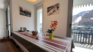 Une pièce avec une table en bois, un banc, une plante en pot et deux tableaux encadrés accrochés au mur.