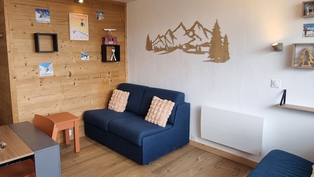 Une pièce chaleureuse avec un canapé bleu, une petite table en bois et un radiateur.