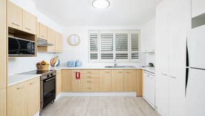 A modern kitchen with wooden cabinets, a microwave, a stove, a sink, and a refrigerator. - Belvedere Bayfront - the tranquillity of waterfront living (Nelson Bay)