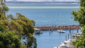 A marina with boats docked, surrounded by trees and a rocky breakwater. - Belvedere Bayfront - the tranquillity of waterfront living (Nelson Bay)