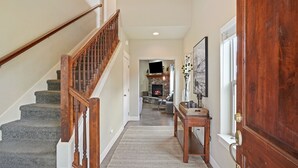 A staircase with wooden railings leading to a living area with a fireplace.