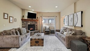 A living room with two sofas, a coffee table, a fireplace, and a TV mounted on the wall.