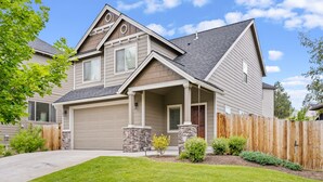 A two-story house with a garage, stone pillars, and a wooden fence.