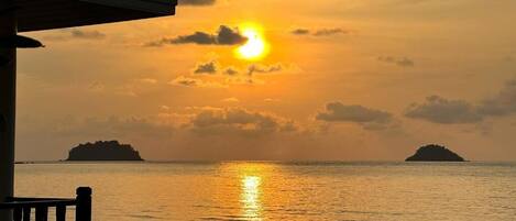 Un coucher de soleil sur une mer calme, avec deux îles à l'horizon.