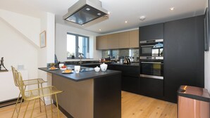 Una cocina moderna con una isla central, electrodomésticos de acero inoxidable y un amplio ventanal.