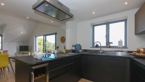 Una cocina moderna con una isla grande, armarios negros y una ventana que proporciona luz natural.