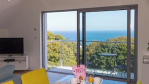 Una habitación moderna con un ventanal grande que ofrece vistas panorámicas del mar y la vegetación.