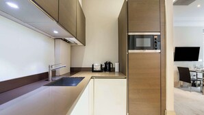 A modern kitchen with a built-in microwave, a coffee maker, and a sink. - Modern Studio in Mayfair next to Hyde Park (London)