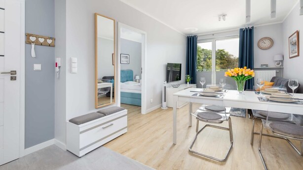 A modern kitchen with a dining area, a bench, and a large mirror.