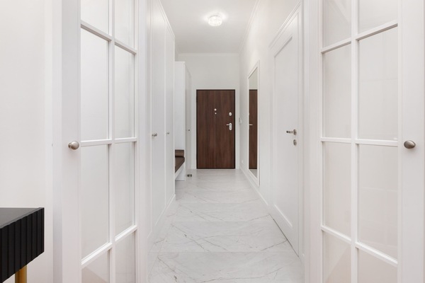 A bright and spacious hallway with white walls, polished floors, and plenty of natural light.