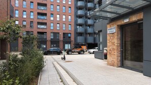 A modern building with a brick facade, a glass entrance, and a sign indicating 'Ximeno 5D'.