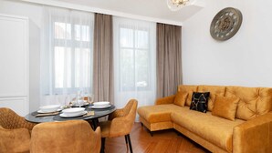 A modern living room with a sofa, dining table, and chairs.