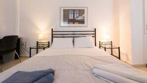 A hotel room with a bed, two bedside tables with lamps, a chair, and a framed picture on the wall. - Studio on Agia Efimia Seaside (Kefalonia)