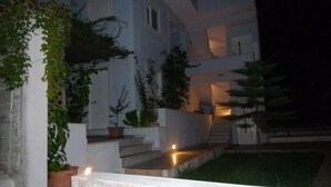 A modern building with a white exterior, multiple floors, and a staircase leading to the entrance. - Studio on Agia Efimia Seaside (Kefalonia)