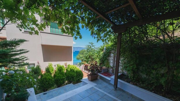A covered outdoor area with a tiled floor, surrounded by greenery and a view of the sea. - Studio on Agia Efimia Seaside (Kefalonia)